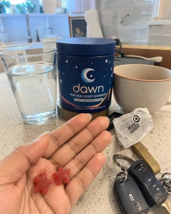 Hand holding two Dawn gummies in kitchen